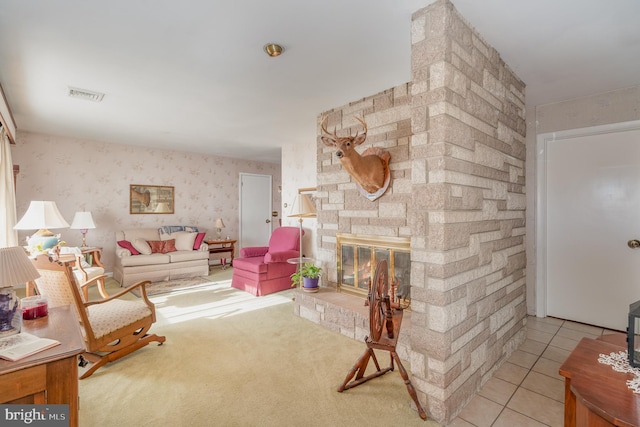 living area featuring light tile patterned floors, a stone fireplace, visible vents, and wallpapered walls