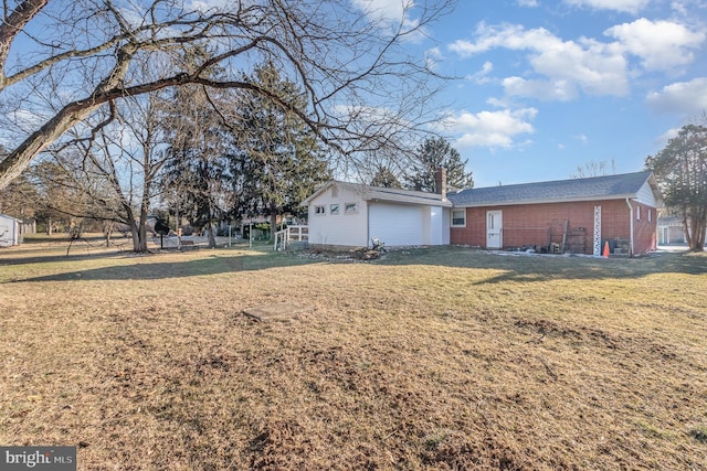 single story home featuring brick siding, a chimney, an outbuilding, and a front yard