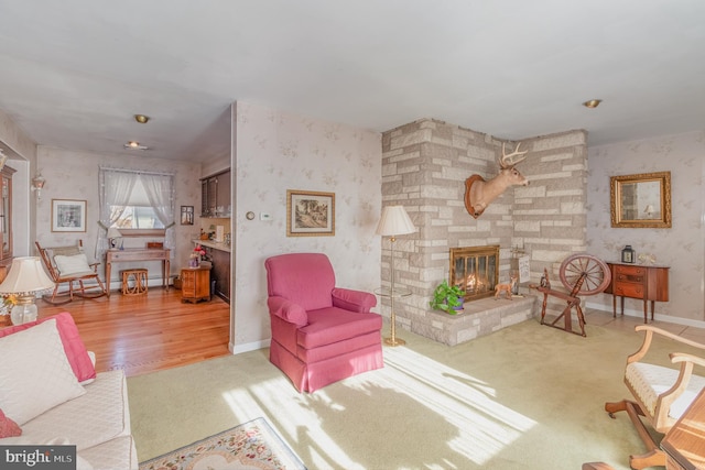 living area featuring wallpapered walls, a fireplace, and baseboards