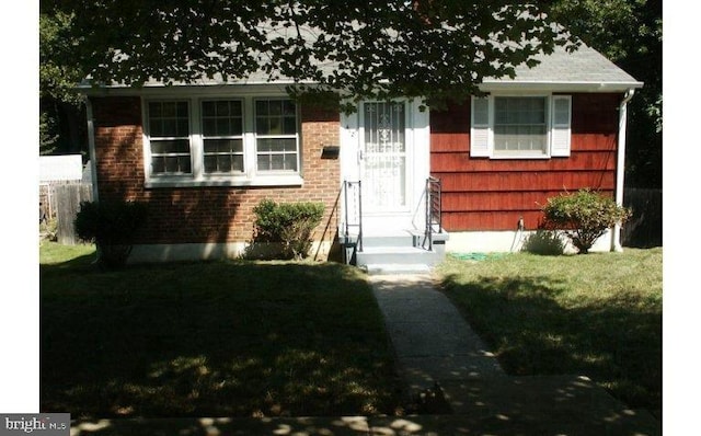 view of front of house featuring entry steps, a front lawn, and brick siding