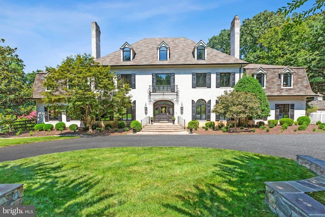 colonial inspired home featuring a chimney and a front lawn