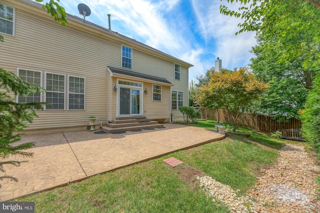 back of property with entry steps, a patio, a lawn, and fence