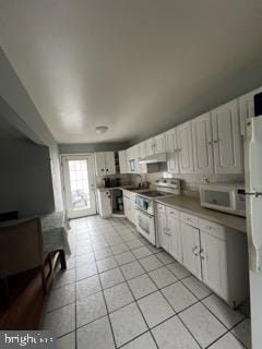 kitchen featuring light tile patterned floors, white cabinetry, stainless steel appliances, and under cabinet range hood