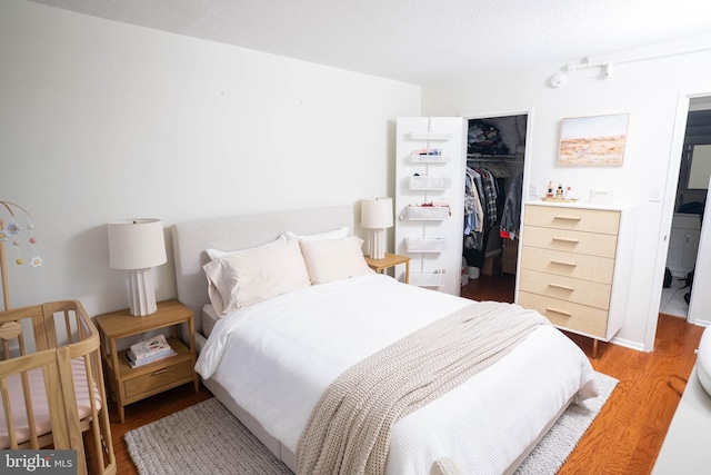 bedroom featuring a closet, a spacious closet, a textured ceiling, and wood finished floors