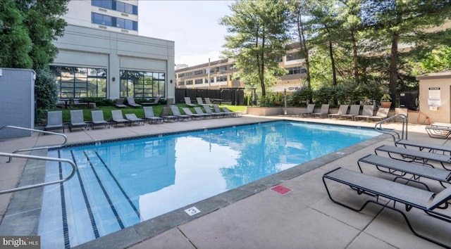 community pool with a patio area and fence