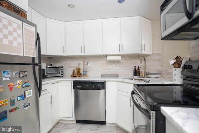 kitchen featuring a toaster, stainless steel appliances, decorative backsplash, white cabinetry, and a sink