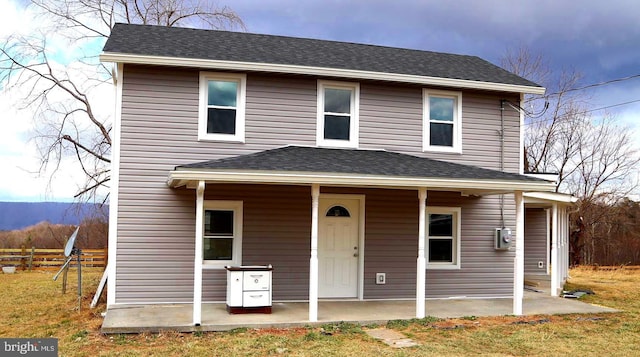 view of front of house featuring a patio area, fence, and roof with shingles