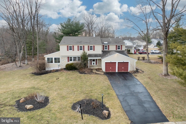 view of front of property featuring driveway, stone siding, a chimney, and a front yard