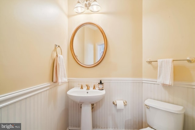 bathroom featuring a wainscoted wall, a sink, and toilet