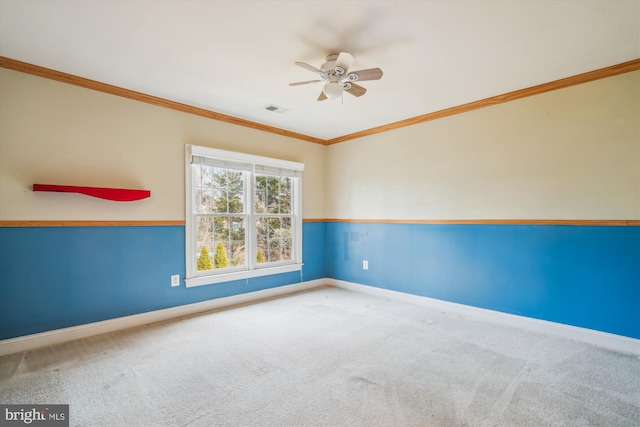 empty room featuring carpet flooring, a ceiling fan, visible vents, baseboards, and ornamental molding