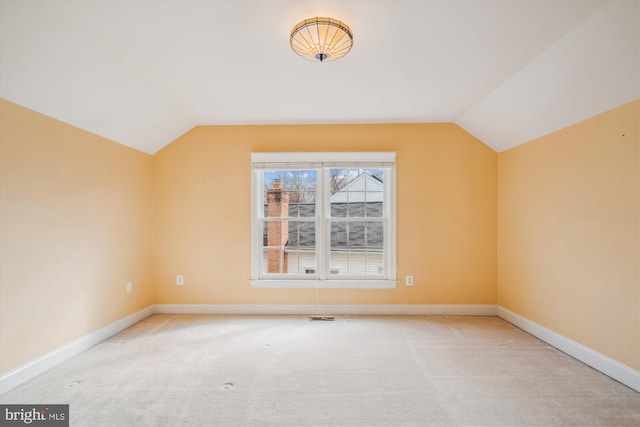 additional living space with lofted ceiling, light colored carpet, visible vents, and baseboards