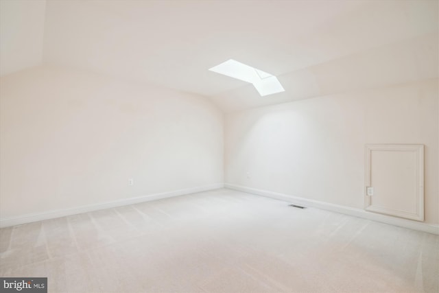 additional living space with lofted ceiling with skylight, light carpet, visible vents, and baseboards