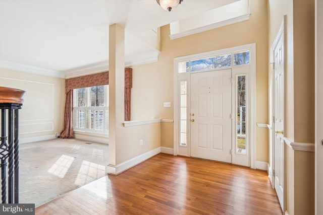 foyer entrance with baseboards, wood finished floors, and crown molding