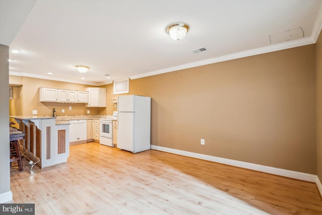 kitchen with a peninsula, white appliances, visible vents, ornamental molding, and a kitchen bar