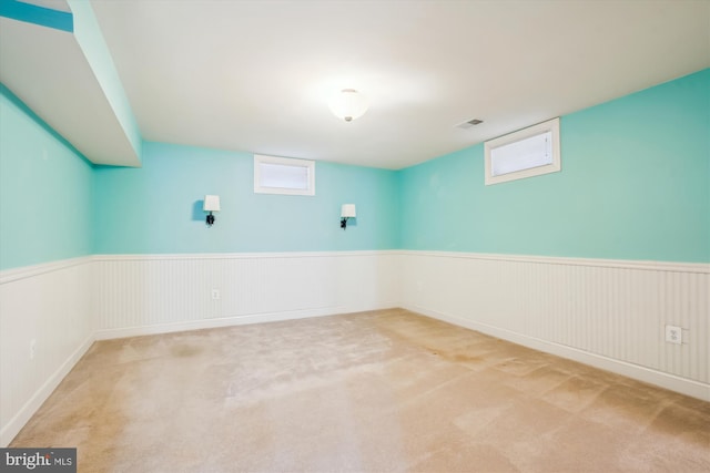 below grade area with carpet floors, a wainscoted wall, and visible vents