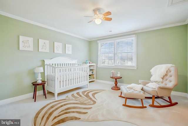 carpeted bedroom with a crib, baseboards, and crown molding