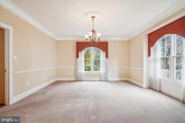 carpeted empty room with a chandelier, crown molding, and baseboards