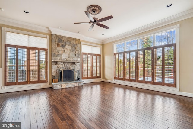 unfurnished living room with a stone fireplace, wood finished floors, a wealth of natural light, and crown molding