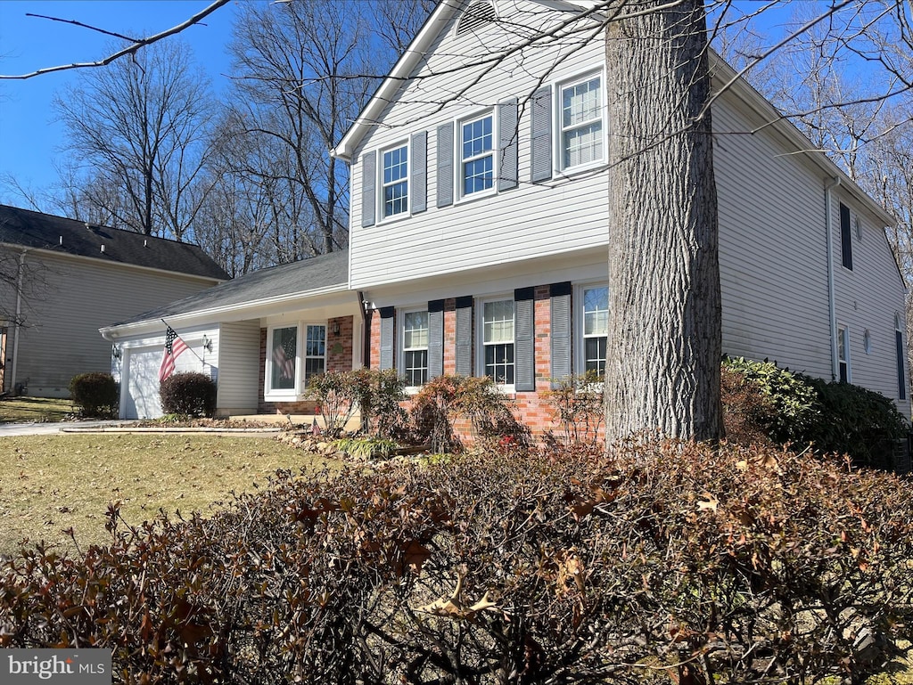 view of front of home with a garage, brick siding, and a front lawn