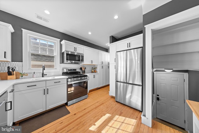 kitchen featuring appliances with stainless steel finishes, a sink, and white cabinetry