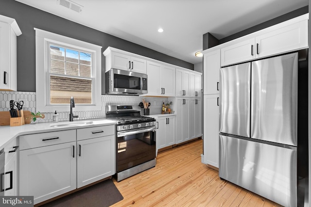 kitchen featuring stainless steel appliances, white cabinets, and a sink