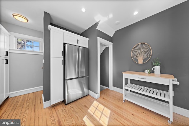 kitchen featuring recessed lighting, light wood-style floors, white cabinets, baseboards, and stainless steel refrigerator