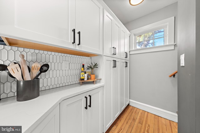 bar with light wood finished floors, tasteful backsplash, and baseboards