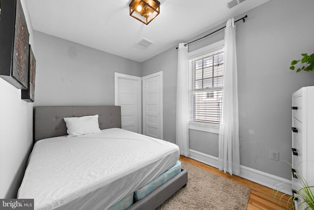 bedroom featuring visible vents, baseboards, and wood finished floors