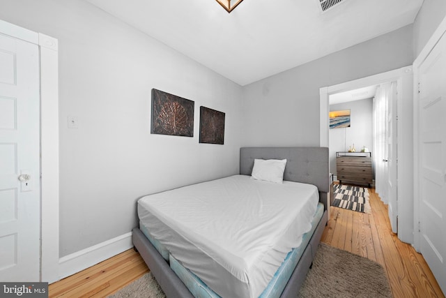 bedroom featuring visible vents, baseboards, and wood finished floors