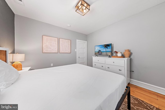 bedroom with visible vents, baseboards, and wood finished floors