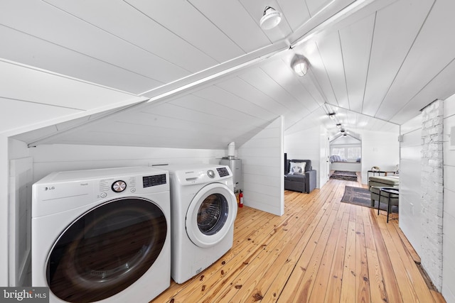 laundry area with laundry area, wooden walls, wood ceiling, washing machine and clothes dryer, and light wood-type flooring