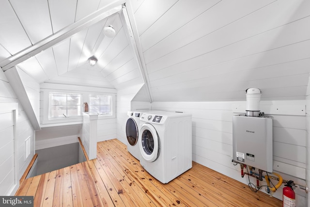 clothes washing area featuring light wood-type flooring, laundry area, wooden walls, and independent washer and dryer