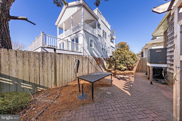 view of patio with fence and a balcony