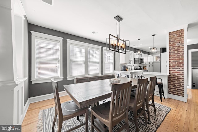 dining area featuring an inviting chandelier, light wood-style flooring, visible vents, and baseboards