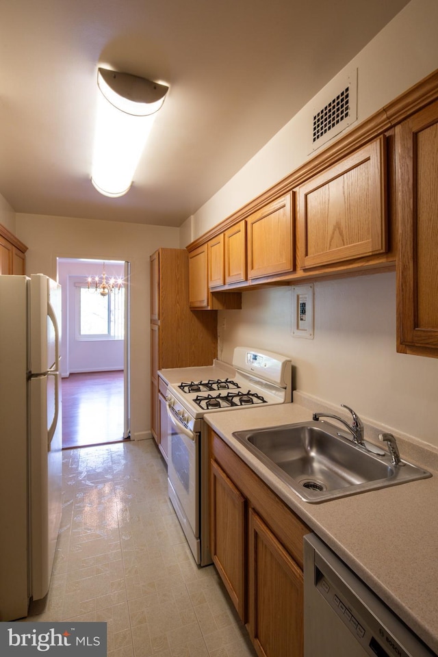kitchen featuring a sink, visible vents, an inviting chandelier, white appliances, and brown cabinets