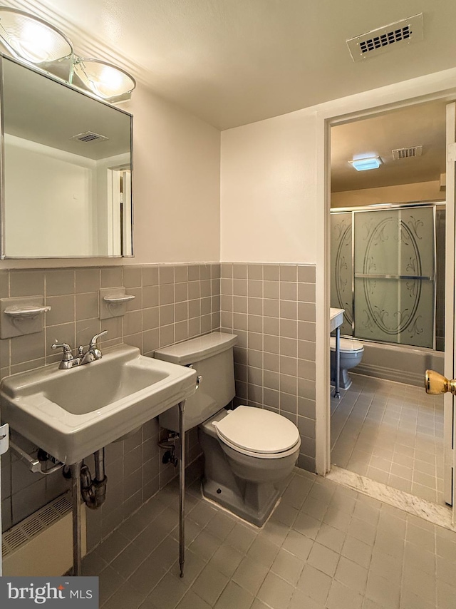 bathroom with combined bath / shower with glass door, visible vents, toilet, and tile patterned flooring