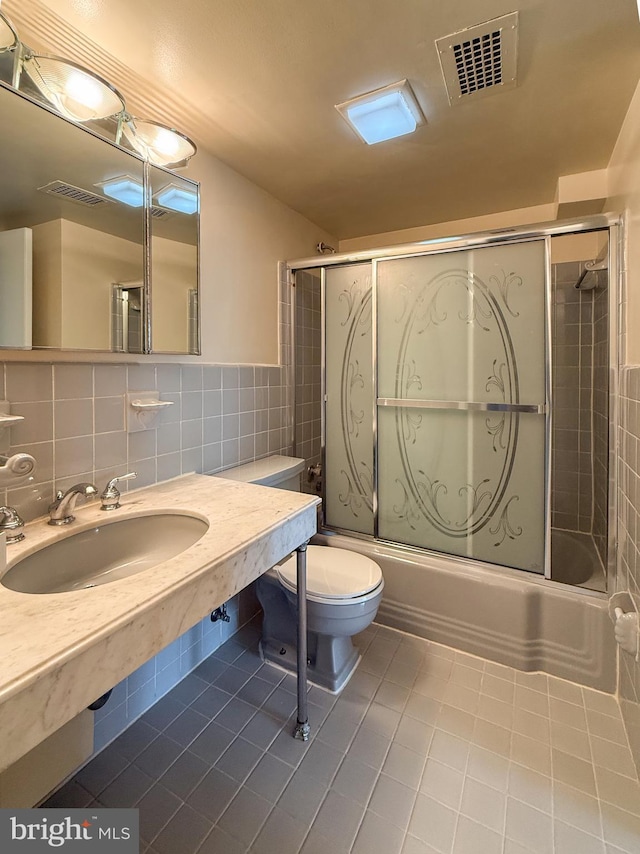 bathroom featuring tile patterned flooring, visible vents, a sink, and enclosed tub / shower combo