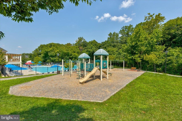 communal playground featuring a community pool, a lawn, and fence