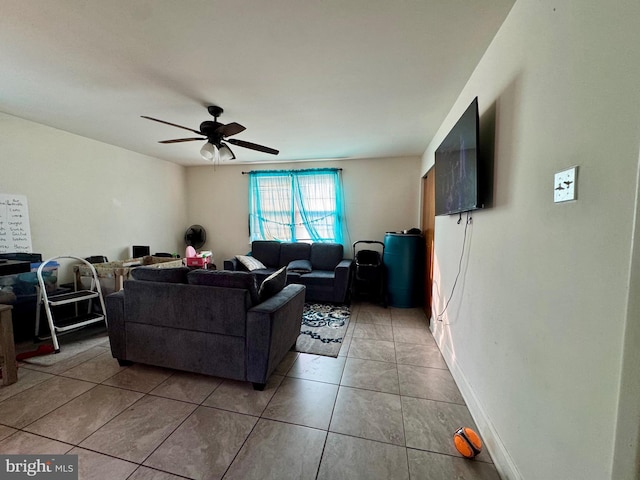 living room with ceiling fan, baseboards, and light tile patterned flooring