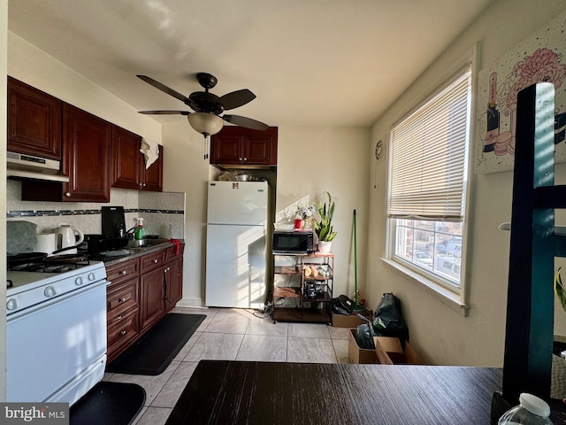 kitchen featuring light tile patterned floors, under cabinet range hood, white appliances, a ceiling fan, and decorative backsplash