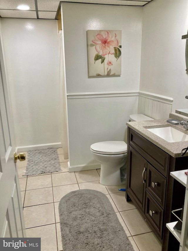 full bath with toilet, a shower with curtain, tile patterned flooring, vanity, and a paneled ceiling