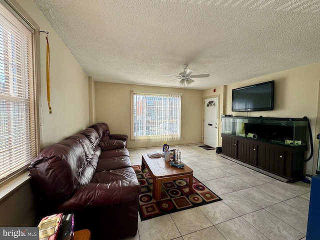 living area featuring ceiling fan, a textured ceiling, and light tile patterned flooring