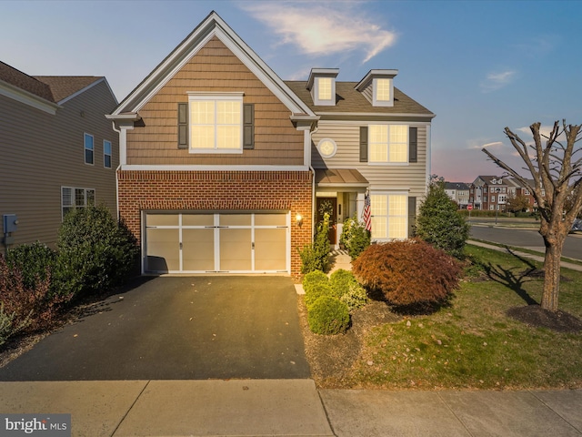 traditional home with aphalt driveway, brick siding, and an attached garage