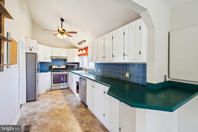 kitchen featuring appliances with stainless steel finishes, dark countertops, a sink, and white cabinetry