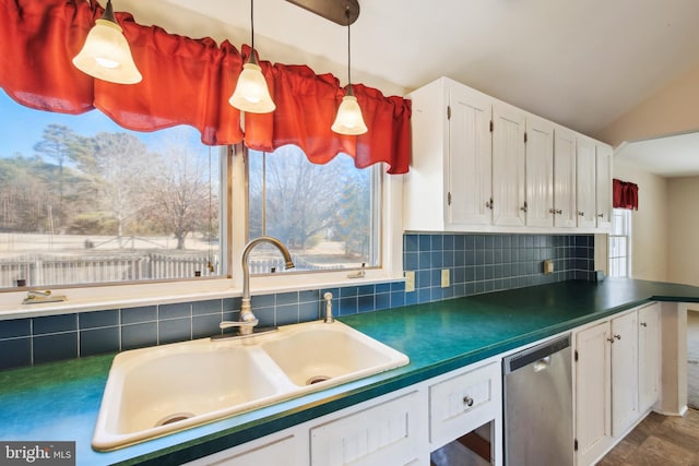 kitchen featuring tasteful backsplash, dark countertops, white cabinetry, a sink, and dishwasher