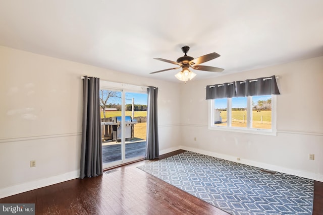 spare room featuring dark wood-style floors, plenty of natural light, and baseboards