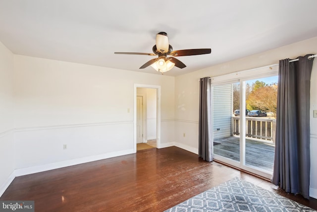 unfurnished room with a ceiling fan, baseboards, and dark wood-type flooring