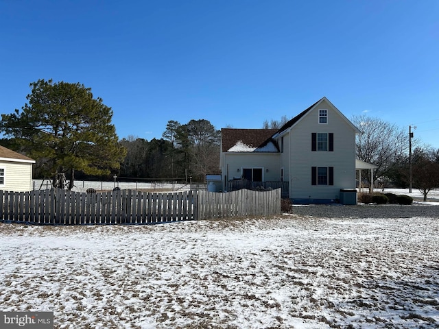 snow covered rear of property with a fenced front yard