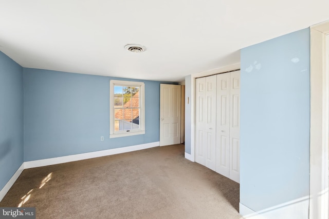 unfurnished bedroom featuring carpet, baseboards, visible vents, and a closet