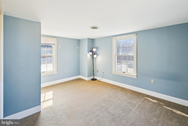 unfurnished room featuring carpet floors, visible vents, and baseboards